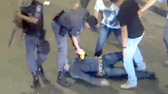 Um policial militar foi flagrado usando uma arma de choque contra um homem que estava caído no chão