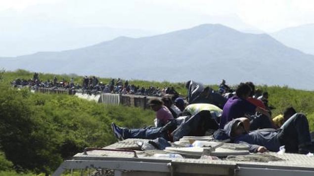 Pessoas que esperam entrar nos EUA sobre vagões de trem na cidade mexicana de Ixtepec