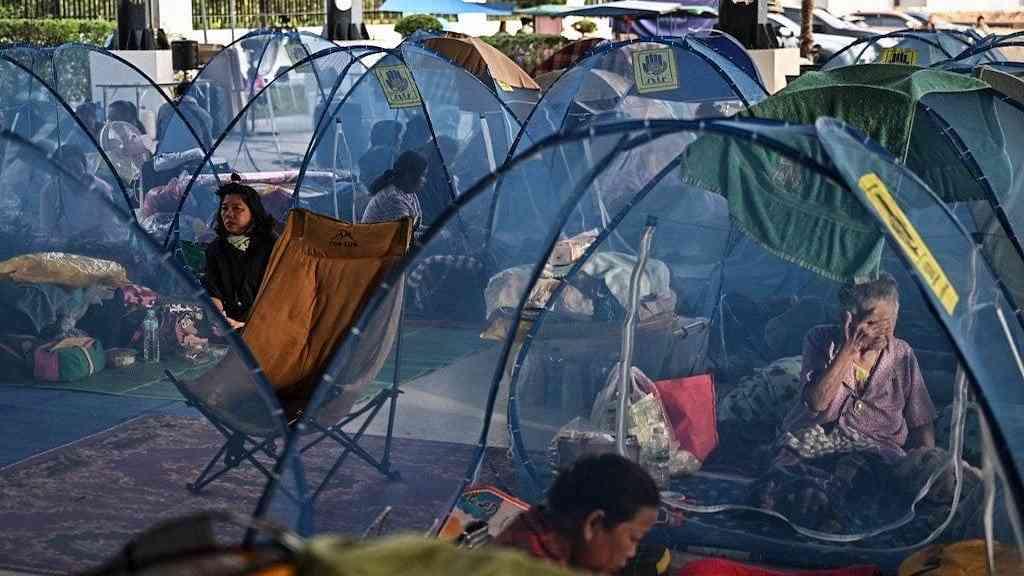 Tensão entre Camboja e Tailândia desloca meio milhão | Moradores deslocados descansam enquanto se abrigam em um centro de evacuação durante confrontos ao longo da fronteira entre a Tailândia e o Camboja, na província tailandesa de Sa Kaeo