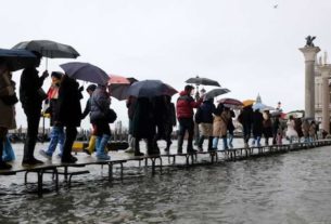 Turistas caminham por passarelas erguidas na Praça de São Marcos