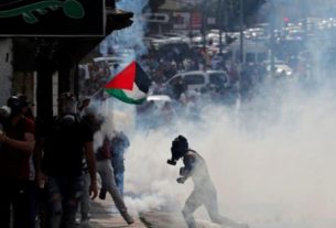 Manifestantes palestinos fogem de fumaça de gás lacrimogêneo lançado por forças israelenes durante protesto contra Israel