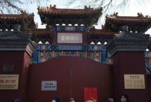 Pessoas em frente a portão de templo na China fechado devido a surto de coronavírus