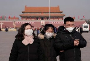 Turistas com máscara de proteção na Praça da Paz Celestial, em Pequim