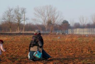Imigrante caminha ao lado de criança em direção à travessia de fronteira da Turquia com a Grécia