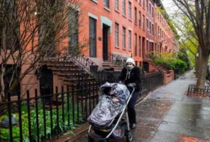 Mulher passeia com seu bebê usando máscara de proteção em Nova York