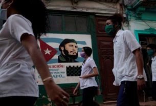 Estudantes de medicina passam por imagem de Fidel Castro durante verificação de sintomas porta a porta durante pandemia de covid-19
