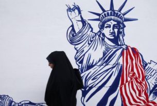 Mulher passa por mural na antiga embaixada dos EUA em Teerã
