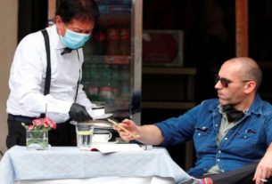 Homem é servido por garçom com máscara de proteção em restaurante de Roma