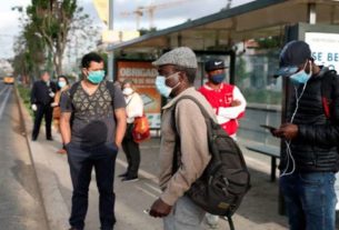 Pessoas com máscaras de proteção em ponto de ônibus em Lisboa
