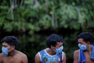 Indígenas com máscaras de proteção contra Covid-19 conversam enquanto agentes de saúde checam moradores de aldeia no Pará
