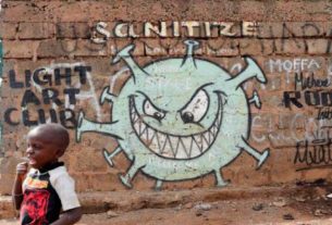 Menino em frente a grafite representando o novo coronavírus em Nairóbi, no Quênia