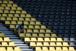Homem acompanha partida do Campeonato Alemão em arquibancada vazia