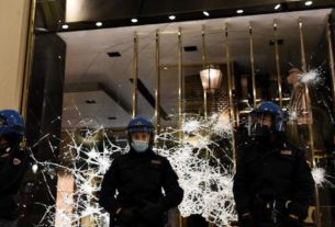 Policias diante de vitrine quebrada durante protesto em Turim