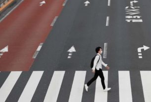 Um homem usando uma máscara protetora atravessa uma rua em Shinjuku, após o surto da doença