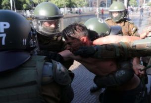 Homem é detido por policiais durante protestos em Santiago, no Chile