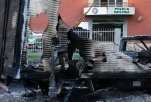 Destroços de caminhão queimado em frente a batalhão de polícia após assalto a banco em Criciúma