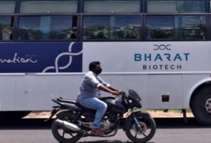 Homem passa de moto por ônibus da empresa indiana Bharat Biotch em frente a sede da companhia em Hyderabad, na Índia