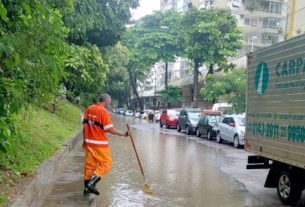 O gari da Comlurb tenta aliviar o volume de peso sobre os pontos de escoamento da água da chuva, no Jardim Botânico